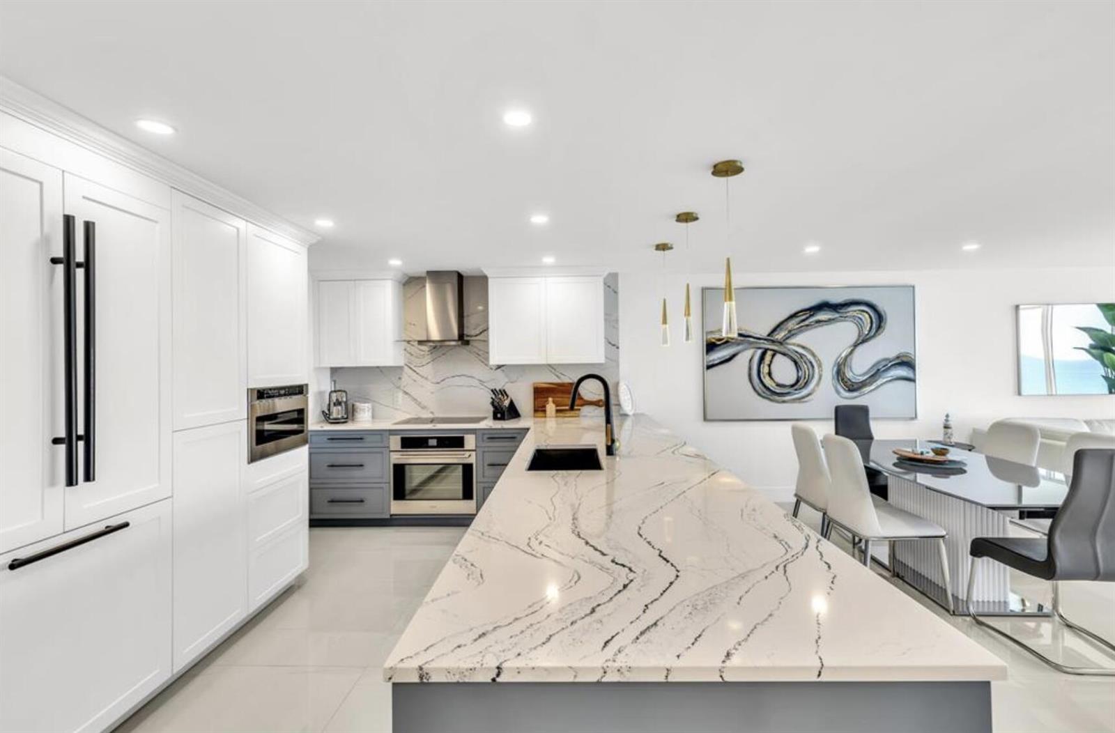 A modern kitchen features a large marble-topped island, white cabinetry, and gray lower cabinets — 3000 S Ocean Boulevard # 1405, Boca Raton FL 33432, BOCA RATON, FL