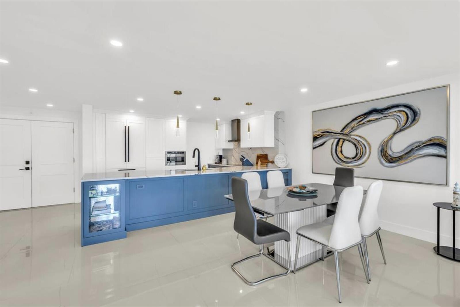 A modern kitchen and dining area features a blue island, white cabinetry, and glass table — 3000 S Ocean Boulevard # 1405, Boca Raton FL 33432, BOCA RATON, FL