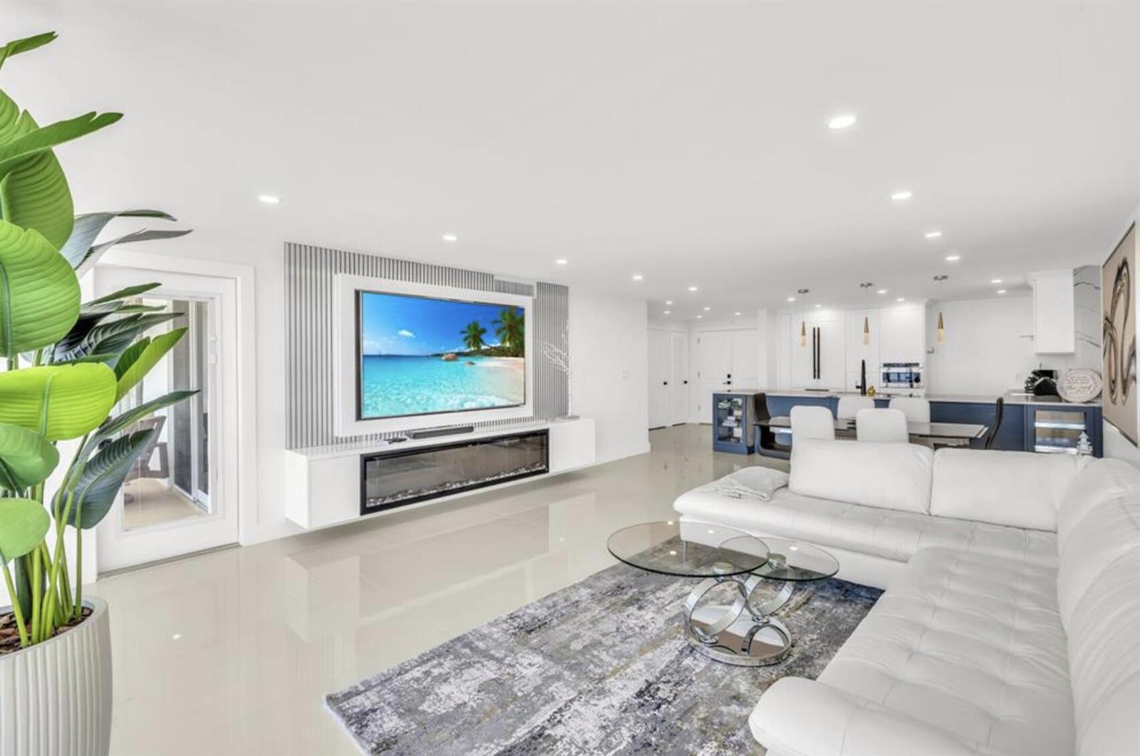 A modern living room features a white sectional sofa, a fireplace, and an open kitchen — 3000 S Ocean Boulevard # 1405, Boca Raton FL 33432, BOCA RATON, FL