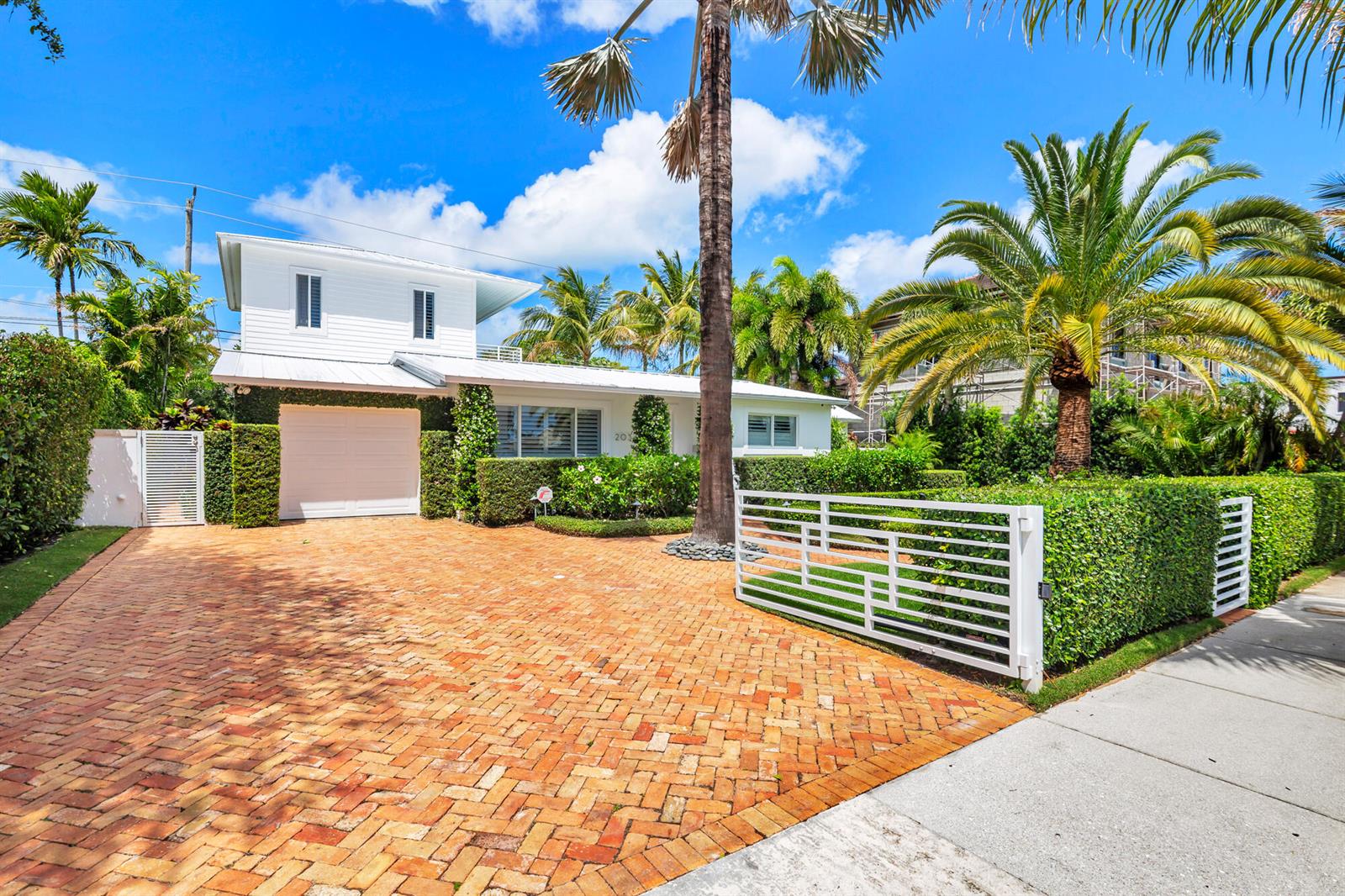 A white two-story house with a brick driveway and a white gate behind palm trees — 203 Arlington Road, West Palm Beach FL 33405, WEST PALM BEACH, FL