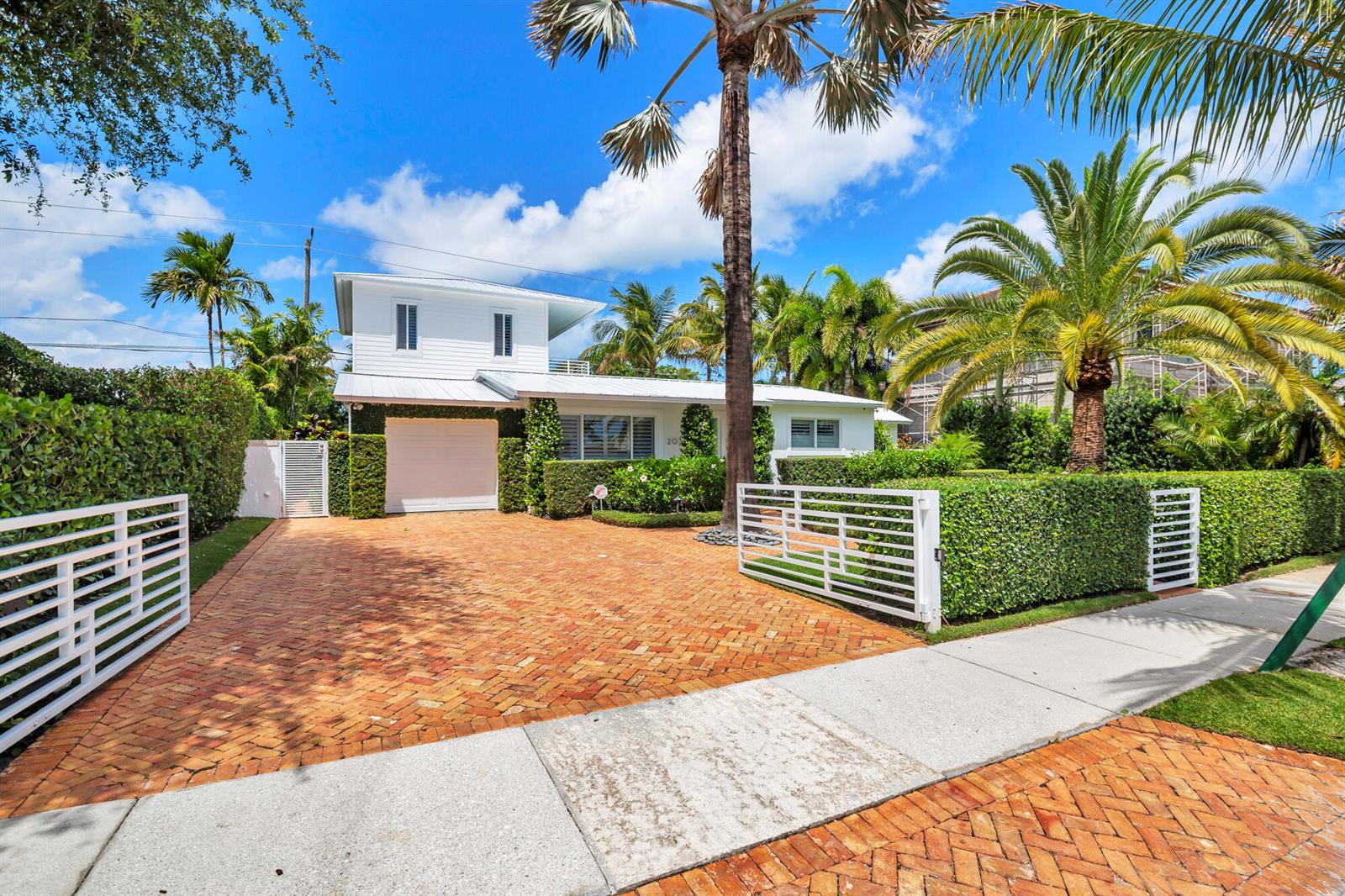 A white two-story house with a brick driveway and a white gate behind a hedge — 203 Arlington Road, West Palm Beach FL 33405, WEST PALM BEACH, FL