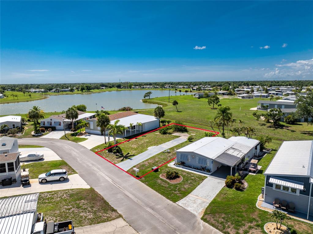 An aerial view shows a vacant residential lot outlined in red between two manufactured homes — 7498 DANVERS CIRCLE, PORT CHARLOTTE, FL