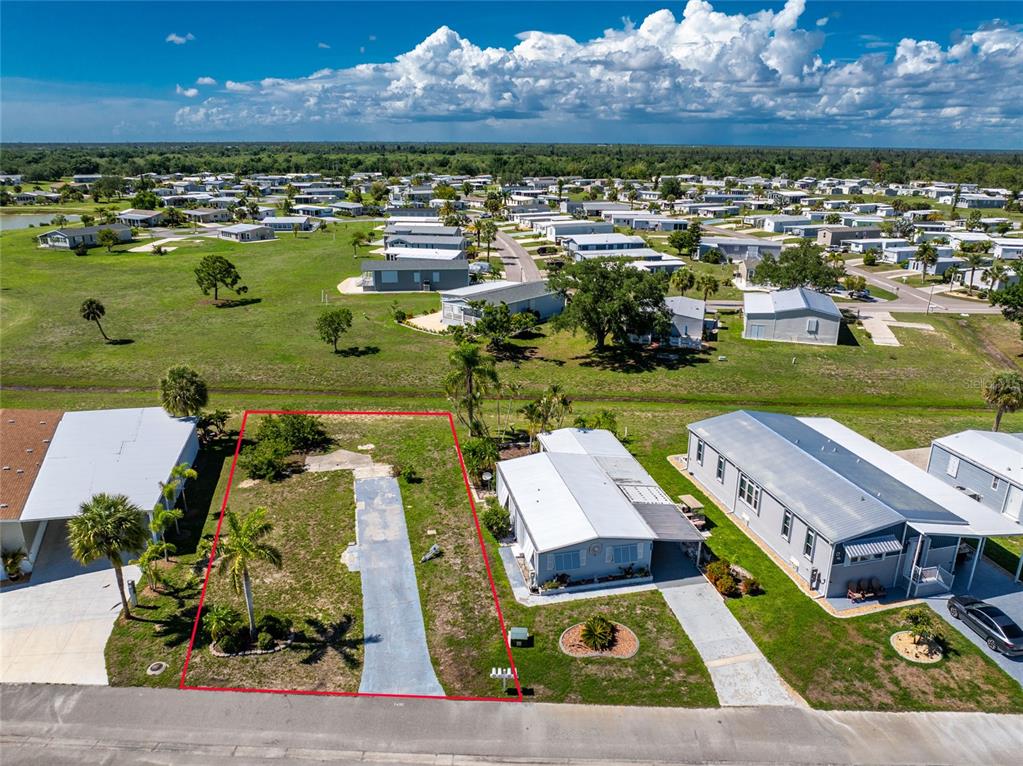 An aerial view shows a vacant residential lot outlined in red next to existing homes — 7498 DANVERS CIRCLE, PORT CHARLOTTE, FL