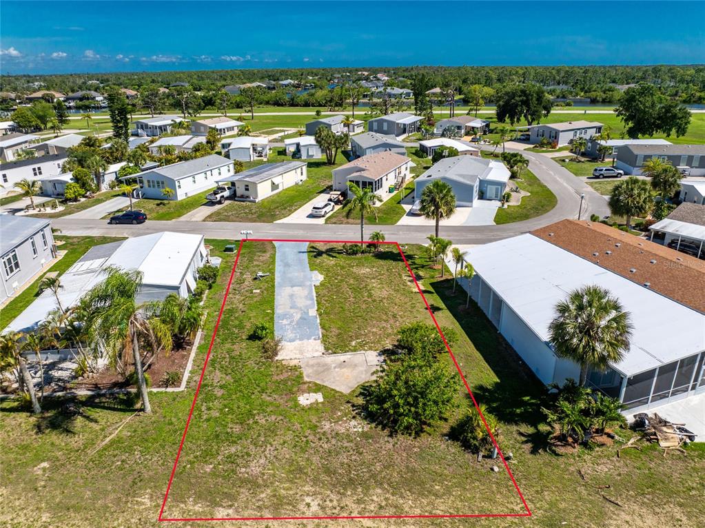 An aerial view shows a vacant residential lot outlined in red within a mobile home community — 7498 DANVERS CIRCLE, PORT CHARLOTTE, FL