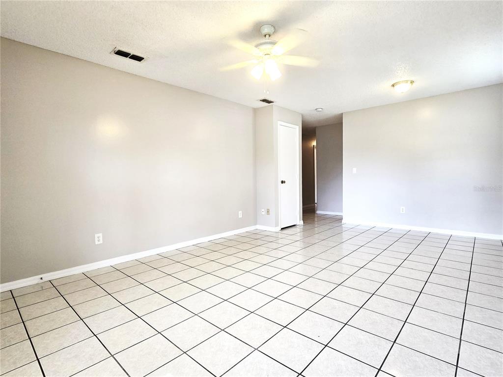 An empty room features light-colored walls, a ceiling fan, and white tiled flooring — 1423 MONTANA AVENUE UNIT 1423, ST CLOUD, FL
