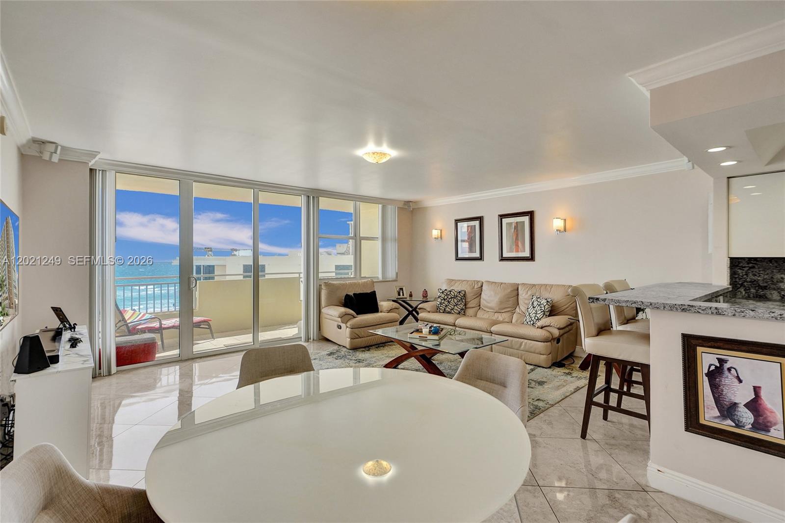 A living and dining area features tile floors, a beige sofa, and a balcony view — 3180 S Ocean Dr # 415, Hallandale Beach FL 33009, HALLANDALE BEACH, FL