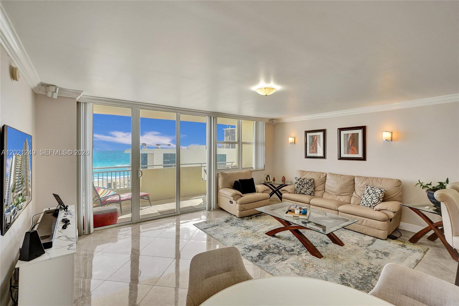 A living room features beige leather furniture, a glass coffee table, and a balcony view — 3180 S Ocean Dr # 415, Hallandale Beach FL 33009, HALLANDALE BEACH, FL