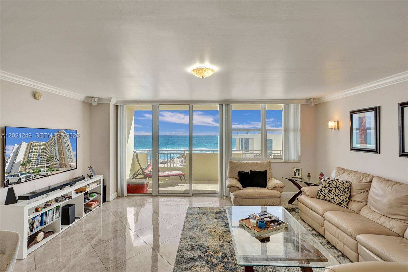 A living room features beige leather furniture, a glass coffee table, and ocean views — 3180 S Ocean Dr # 415, Hallandale Beach FL 33009, HALLANDALE BEACH, FL