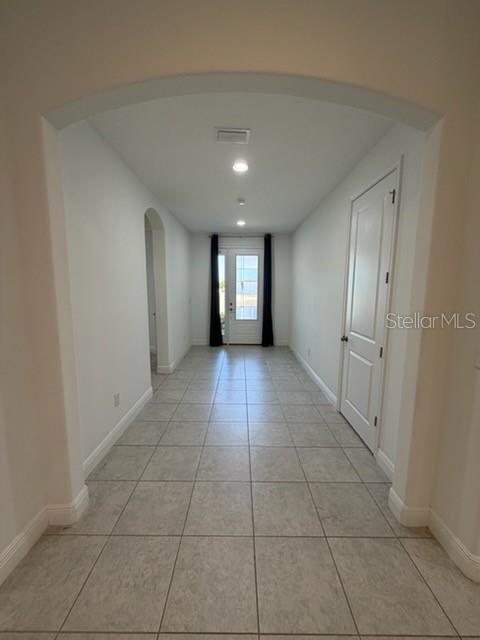 A tiled hallway features an arched entryway, recessed lighting, and a door leading outside — 3918 GAVIOTA DRIVE, SUN CITY CENTER, FL