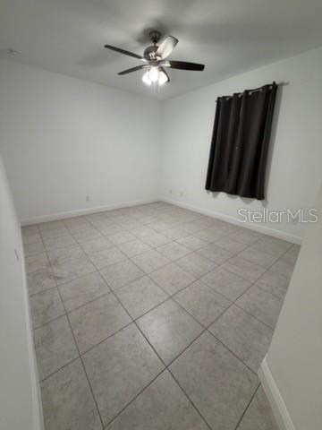 An empty bedroom features light-colored tile flooring, white walls, and a ceiling fan — 3918 GAVIOTA DRIVE, SUN CITY CENTER, FL