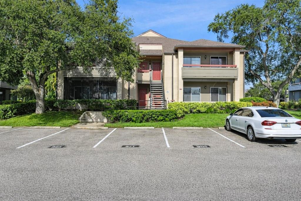 A two-story apartment building with a parking lot in the foreground and surrounding trees — 10263 GANDY BOULEVARD N UNIT 602, ST PETERSBURG, FL