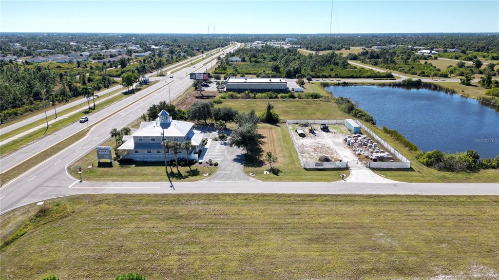 An aerial view shows a commercial building, a fenced storage lot, and a nearby pond — 8379 GASPARILLA ROAD, ROTONDA WEST, FL