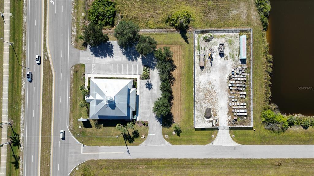 An aerial view shows a commercial building with a parking lot next to a fenced lot — 8379 GASPARILLA ROAD, ROTONDA WEST, FL