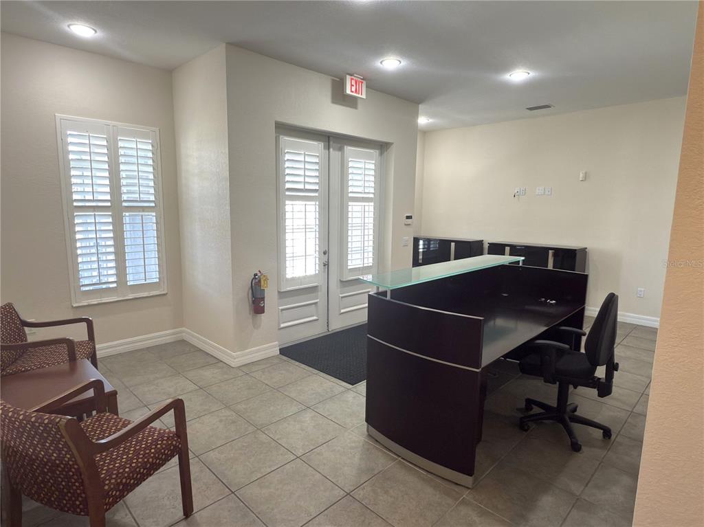 A reception area features a dark desk, two patterned chairs, and double glass doors — 8379 GASPARILLA ROAD, ROTONDA WEST, FL