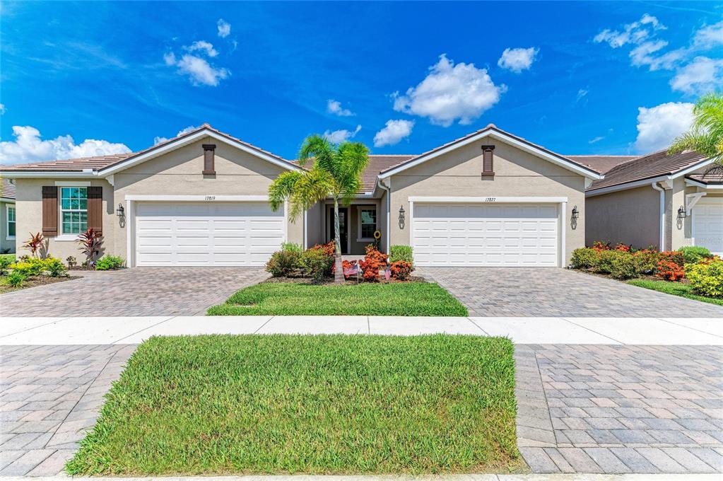 A duplex home features two garage doors, a shared entryway, and a paved driveway — 17827 STILLNESS COURT, VENICE, FL