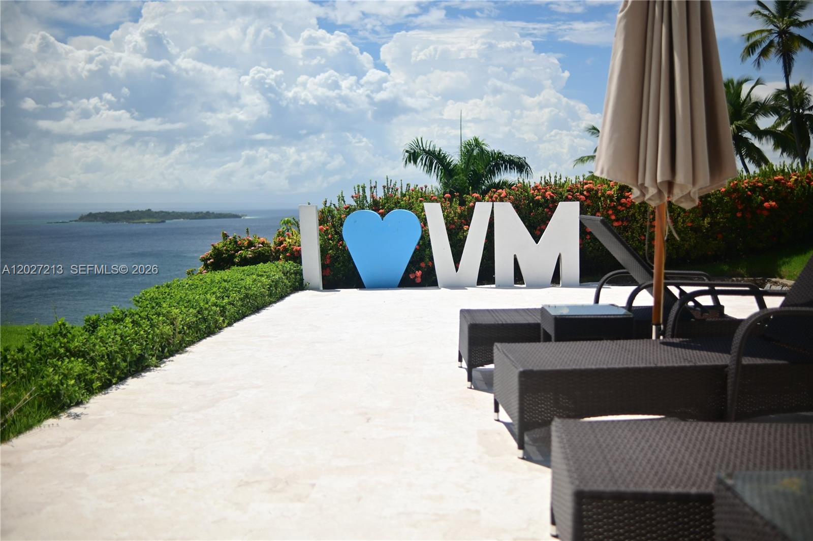 A patio features lounge chairs, an umbrella, and a large sign reading I [heart] VM — Highway#5 Vista Mare # 102, FL 32000, FL