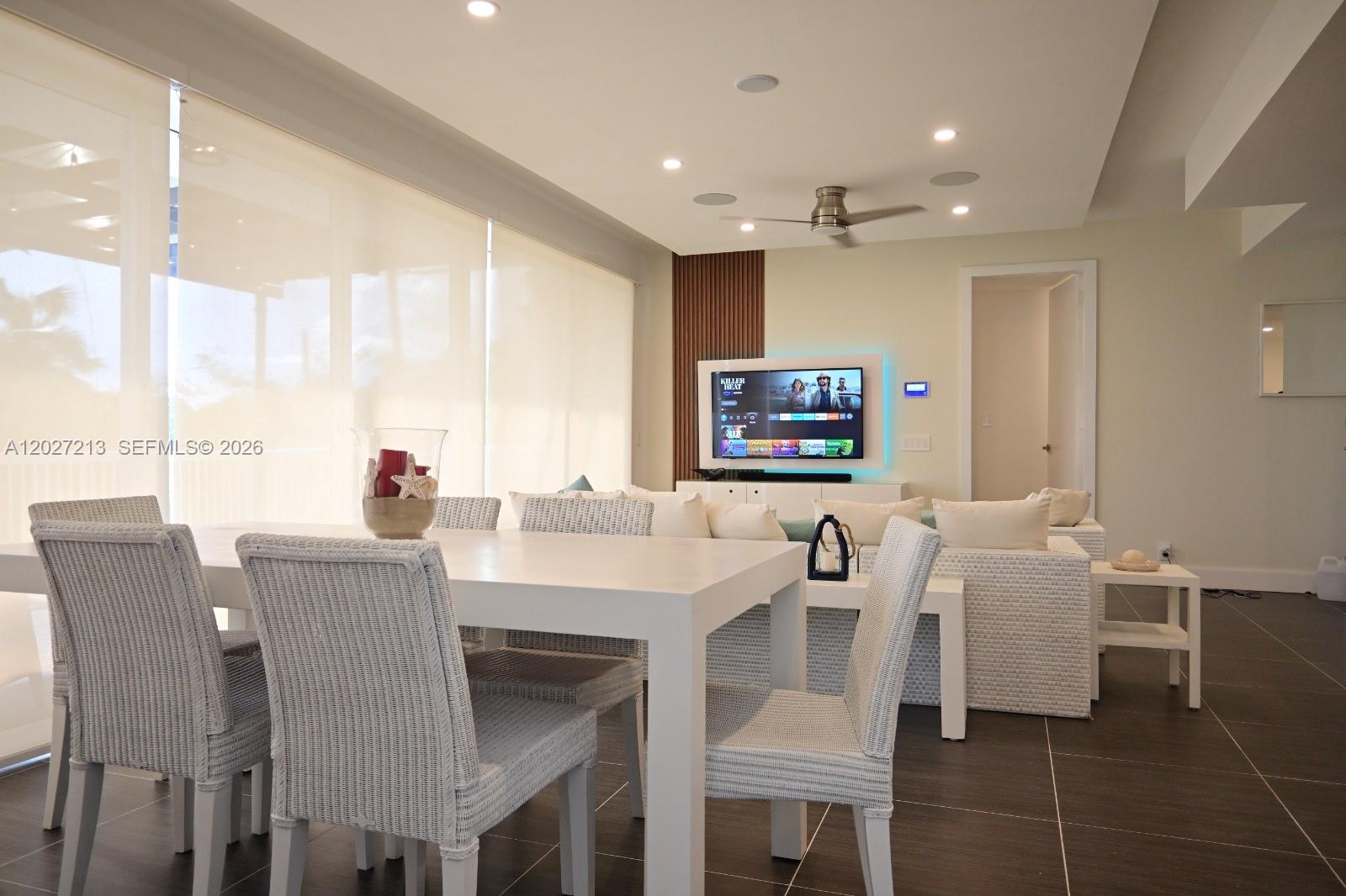 A dining area with white wicker chairs sits in front of a living room space — Highway#5 Vista Mare # 102, FL 32000, FL