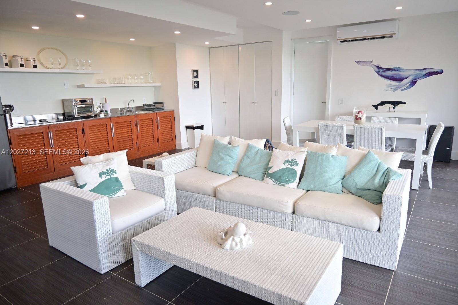 A living room with white wicker furniture, a kitchenette with wooden cabinets, and dining area — Highway#5 Vista Mare # 102, FL 32000, FL