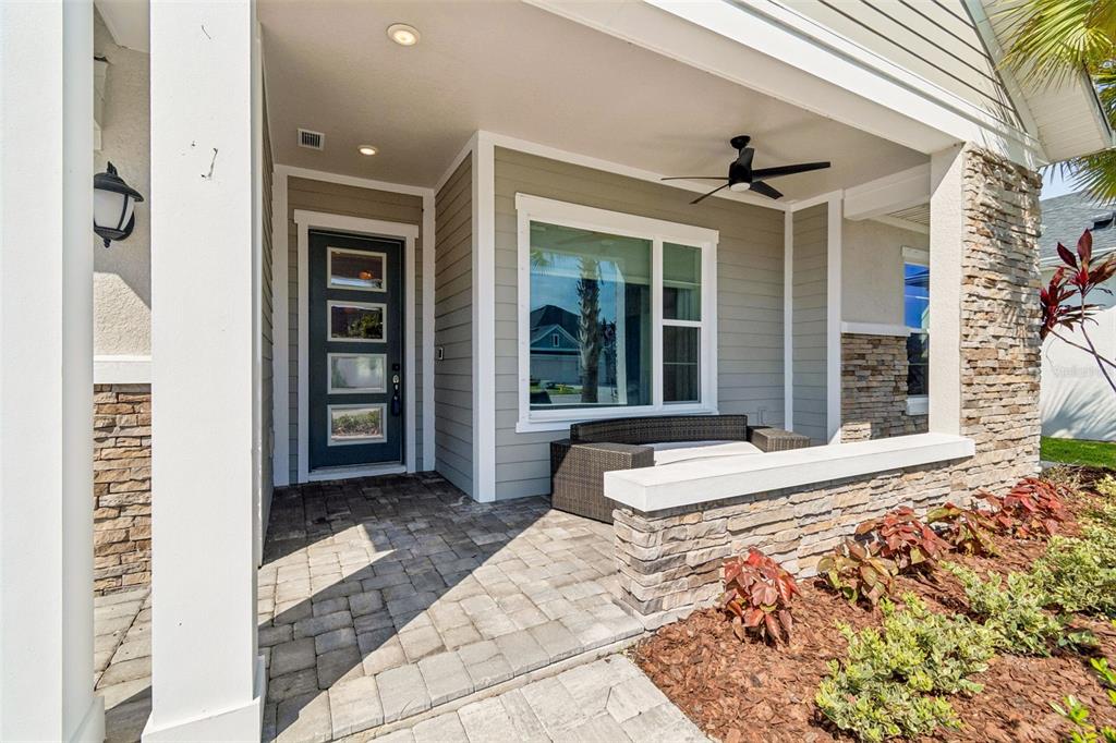A covered front porch features stone accents, a dark door, and a wicker bench — 6107 NIKKI LANE LANE, ODESSA, FL