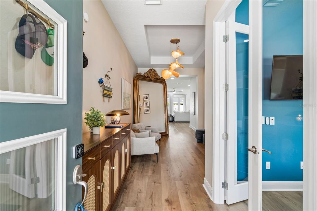 A bright entryway features wood floors, a console table, a large ornate mirror, and lighting — 6107 NIKKI LANE LANE, ODESSA, FL