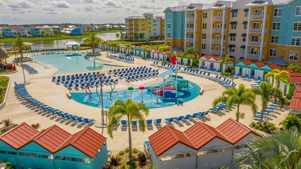 An aerial view of a resort pool area with lounge chairs, cabanas, and a splash pad — 3151 SUNSET WALK DRIVE UNIT 518, KISSIMMEE, FL