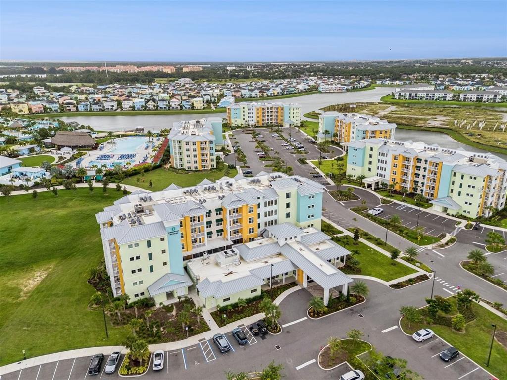 An aerial view shows a multi-story apartment complex with a swimming pool and parking lots — 3151 SUNSET WALK DRIVE UNIT 518, KISSIMMEE, FL