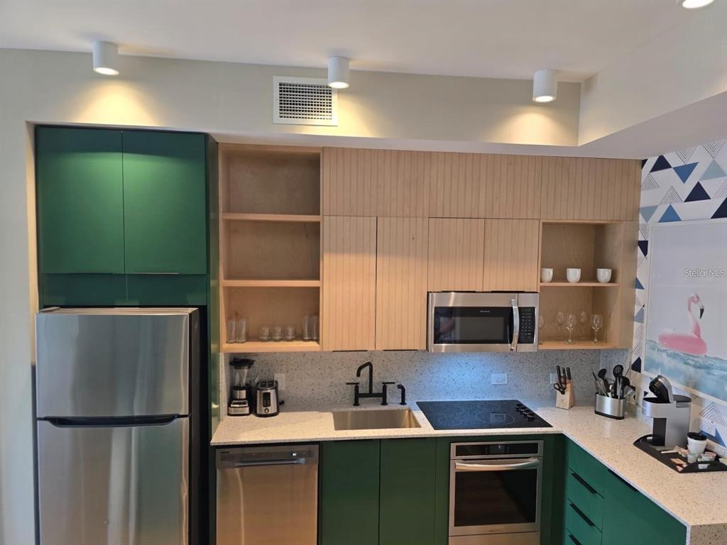 A kitchen features green lower cabinets, light wood upper cabinets, stainless steel appliances, and countertops — 3151 SUNSET WALK DRIVE UNIT 518, KISSIMMEE, FL