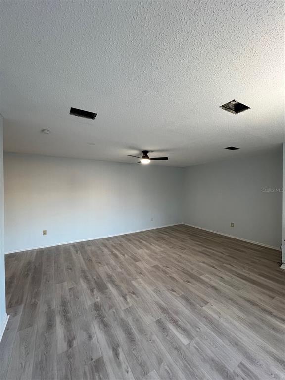 An empty room features light gray wood-look flooring, white walls, and a ceiling fan — 7951 58TH AVENUE N UNIT 207, ST PETERSBURG, FL