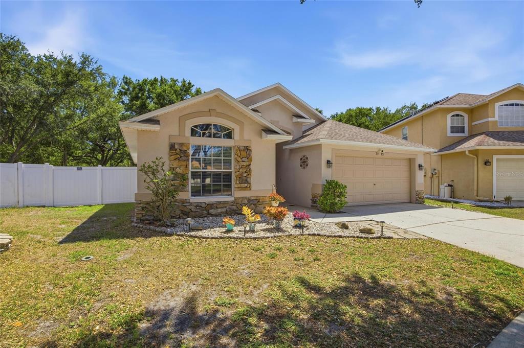 A single-story house with a beige stucco exterior, stone accents, and a two-car garage — 7113 COLONY POINTE DRIVE, RIVERVIEW, FL