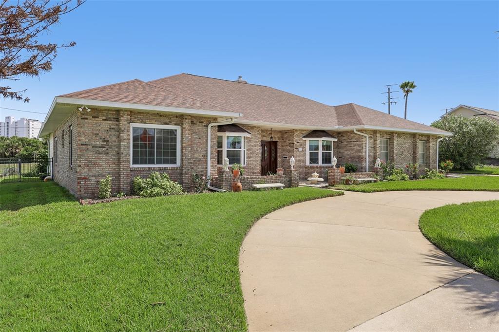 A single-story brick house with a curved concrete driveway and a large front lawn — 235 ANN RUSTIN DRIVE, ORMOND BEACH, FL