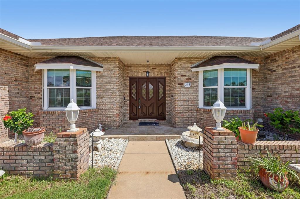 A brick house exterior features a central front door, two bay windows, and stone walkways — 235 ANN RUSTIN DRIVE, ORMOND BEACH, FL