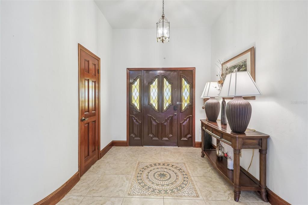 A foyer features a mosaic tile floor inlay, a wooden console table, and double doors — 235 ANN RUSTIN DRIVE, ORMOND BEACH, FL