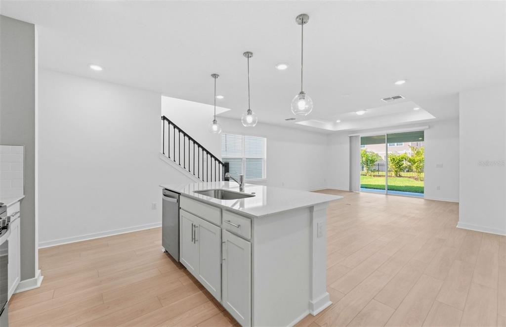 A kitchen island with a sink sits in an open-concept room with light wood flooring — 5344 SPRING MAIDEN CIRCLE, APOLLO BEACH, FL