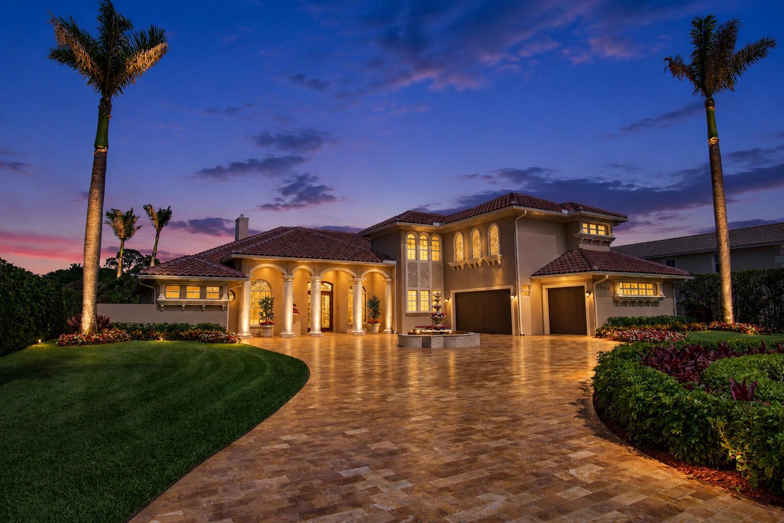 A Mediterranean-style house with a tiled roof, arched entryway, and paved driveway at dusk — 2804 Bent Pine Drive, Fort Pierce FL 34951, FORT PIERCE, FL