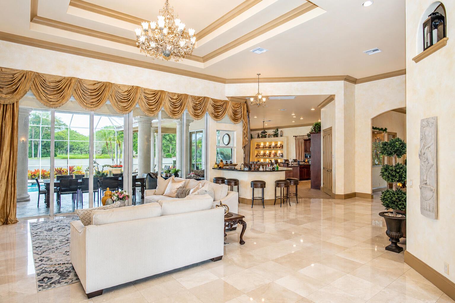 A spacious living room with tile floors, a chandelier, a bar area, and sliding glass doors — 2804 Bent Pine Drive, Fort Pierce FL 34951, FORT PIERCE, FL