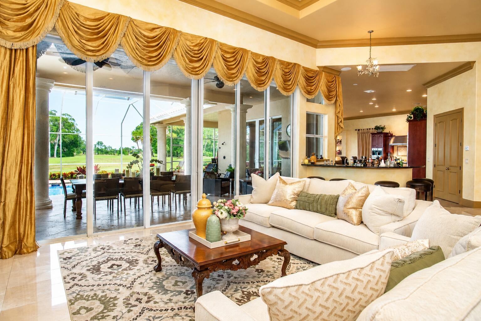 A living room with a cream sofa, patterned rug, and large sliding doors overlooking a pool — 2804 Bent Pine Drive, Fort Pierce FL 34951, FORT PIERCE, FL