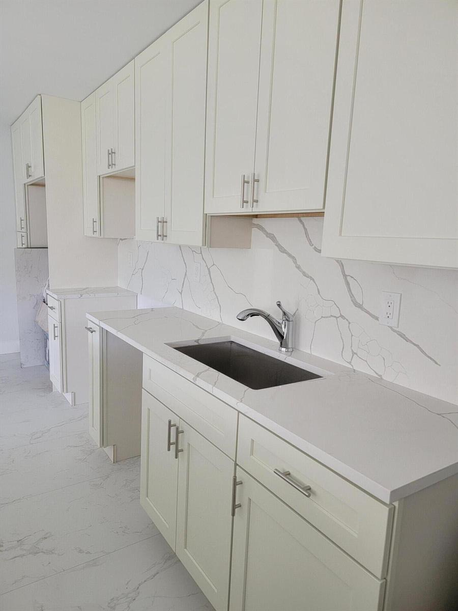 A kitchen features white shaker cabinets, marble-patterned quartz countertops, and a matching backsplash — 240 SW 7th Street # 9, Boca Raton FL 33432, BOCA RATON, FL