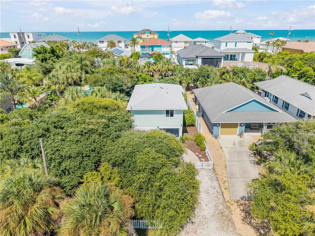 An aerial view shows two houses surrounded by dense trees near a coastal beach — 2722 ANNETTE STREET, FLAGLER BEACH, FL