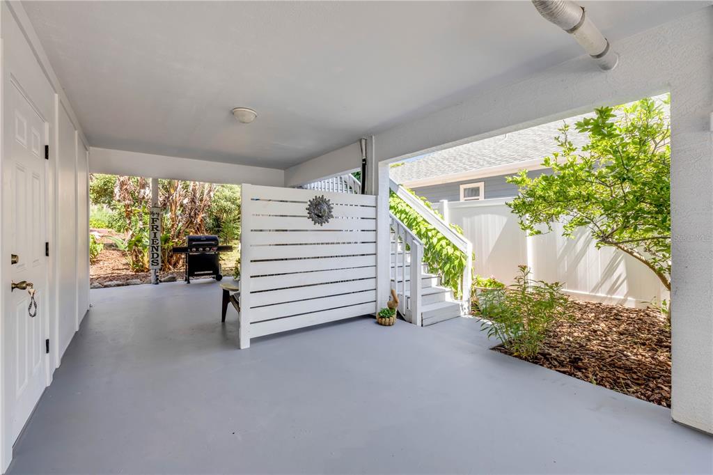 A covered patio features a gray concrete floor, a white privacy screen, and outdoor stairs — 2722 ANNETTE STREET, FLAGLER BEACH, FL