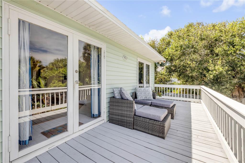 A wooden deck features two gray wicker lounge chairs outside a house with light green siding — 2722 ANNETTE STREET, FLAGLER BEACH, FL