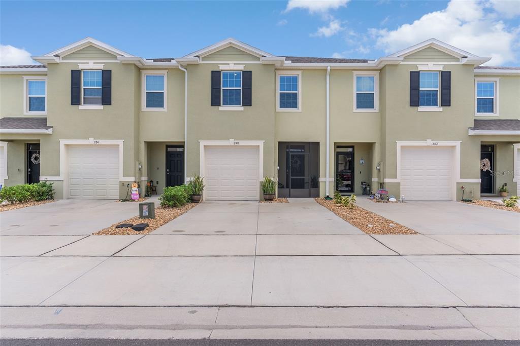 A row of three attached townhouses with light green stucco exteriors and concrete driveways — 1198 LIDO DRIVE, HOWEY IN THE HILLS, FL