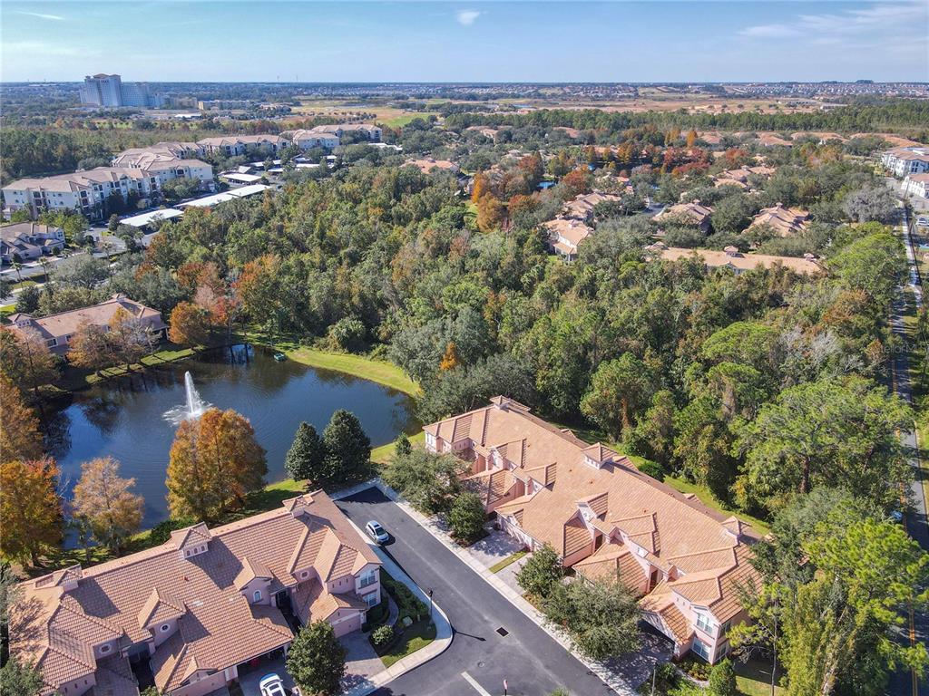 An aerial view shows townhomes with terracotta roofs situated next to a pond with fountains — 1300 GILFORD POINT LANE, DAVENPORT, FL