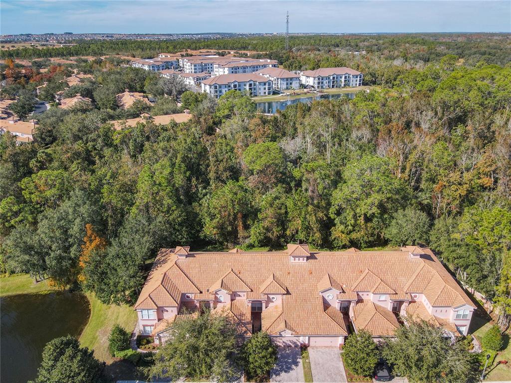 An aerial view shows a multi-unit residential building with a tiled roof near a pond — 1300 GILFORD POINT LANE, DAVENPORT, FL