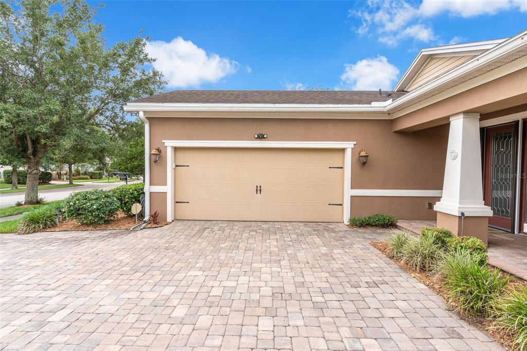 A beige garage with a paved driveway and a covered entryway on the right side — 903 VICTORIA HILLS DRIVE S, DELAND, FL