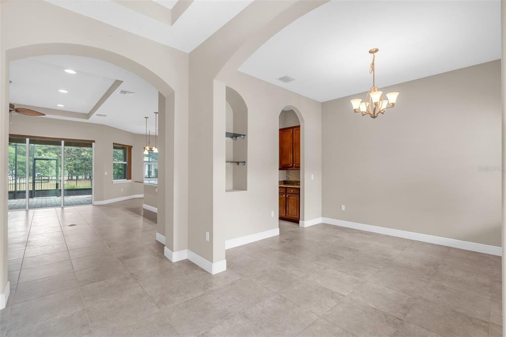 An interior view shows a dining area with tile floors, an arched alcove, and chandelier — 903 VICTORIA HILLS DRIVE S, DELAND, FL