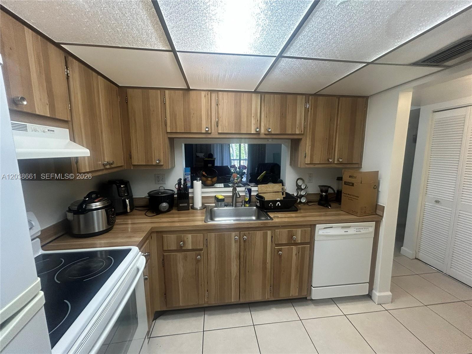 A kitchen features wood cabinets, laminate countertops, a stainless steel sink, and white appliances — 10875 SW 112th Ave # 203, Miami FL 33176, MIAMI, FL