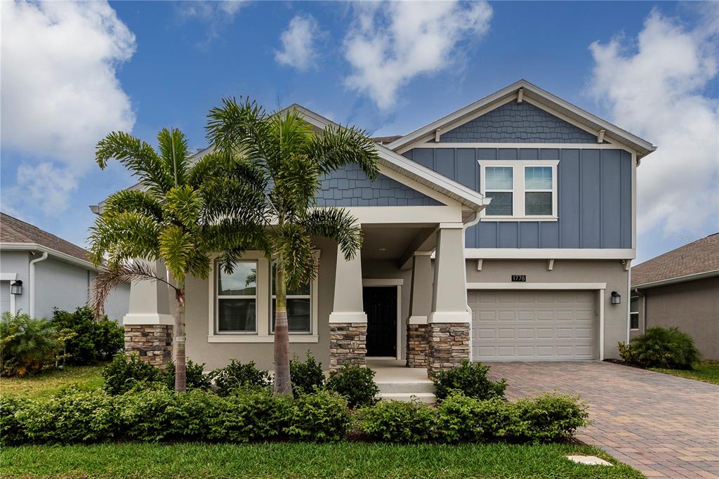 A two-story house with a stone-accented porch, blue siding, and a two-car garage — 1778 BEE NICE DRIVE, KISSIMMEE, FL