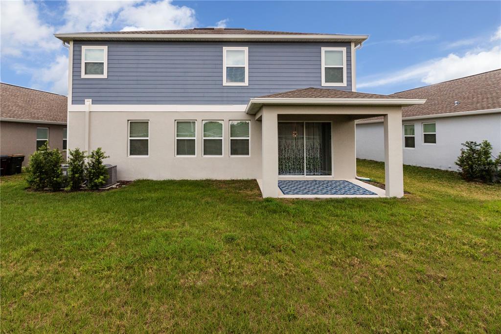 The rear exterior of a two-story house features blue siding, stucco walls, and a patio — 1778 BEE NICE DRIVE, KISSIMMEE, FL