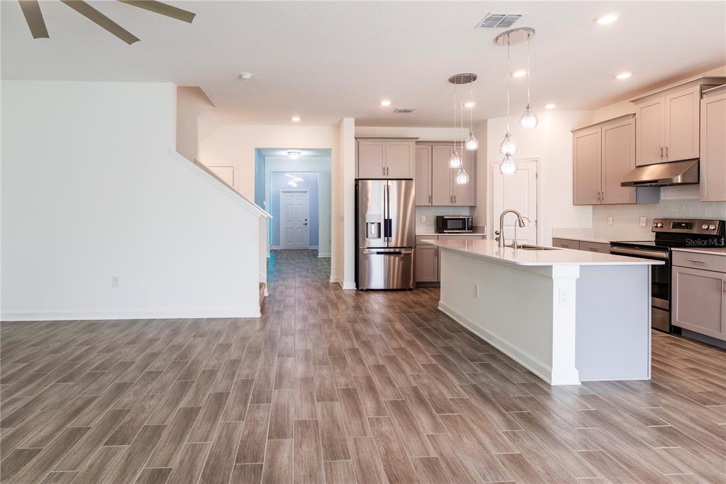 A modern kitchen with gray cabinets, stainless steel appliances, and an island with pendant lighting — 1778 BEE NICE DRIVE, KISSIMMEE, FL