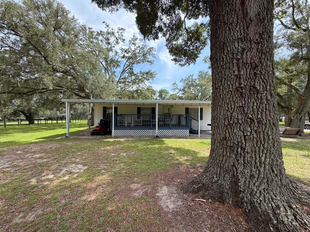 A single-story house with a covered front deck sits on a grassy lot with trees — 7320 SW 22ND STREET, OCALA, FL
